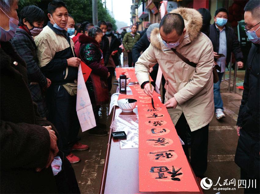 瀘州市文化館在和面鎮(zhèn)義務(wù)書寫贈送春聯(lián)。王奇杰攝