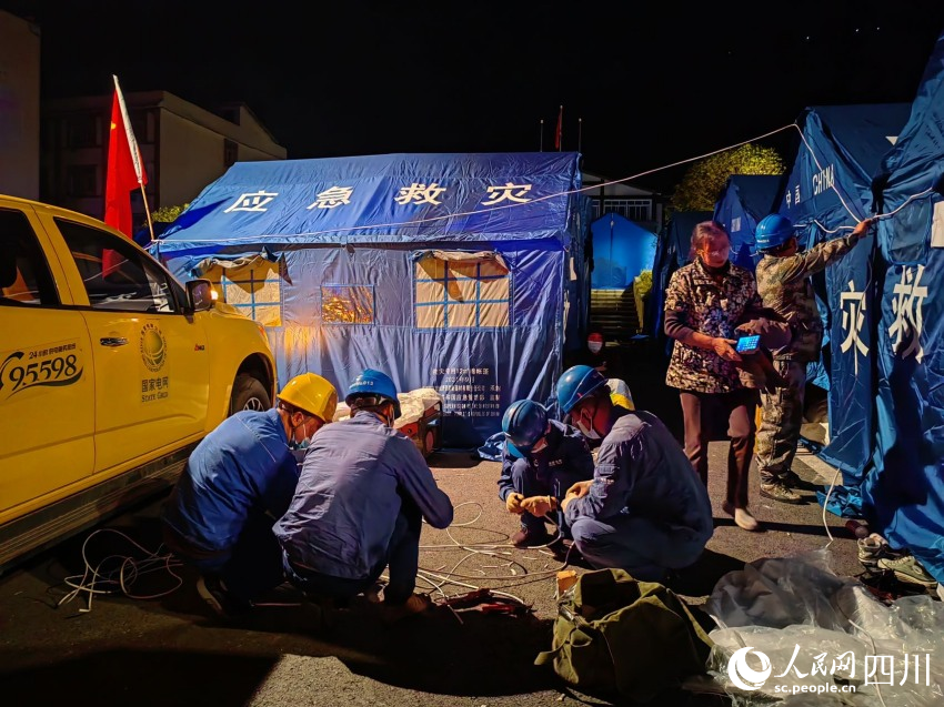 9月5日24時，國網(wǎng)眉山供電公司應急搶險隊員在瀘定縣磨西鎮(zhèn)用應急照明燈點亮磨西鎮(zhèn)公安分局群眾安置點后，馬不停蹄為安置點帳篷通電。王鴻飛攝