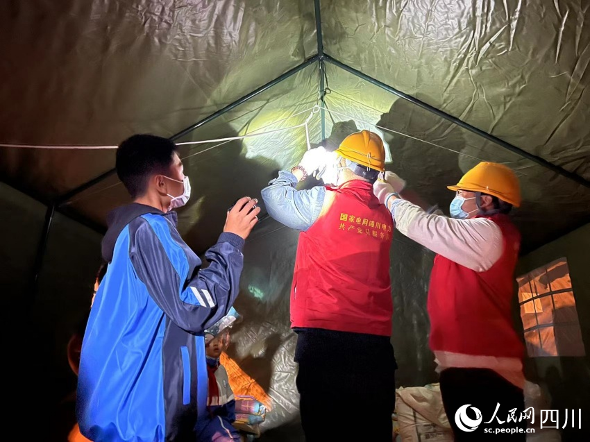 小朋友幫助電力工人照明。湯衛(wèi)攝