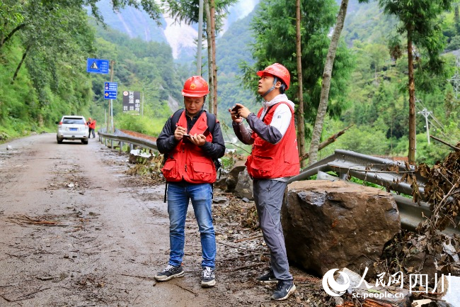 萬利宴（左）和同事在現(xiàn)場進(jìn)行地質(zhì)災(zāi)害隱患排查。人民網(wǎng) 朱虹攝
