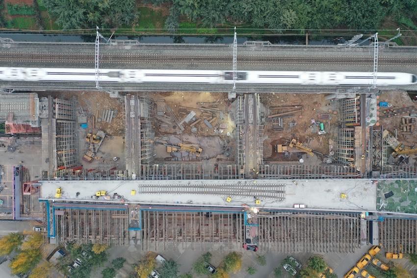 施工現(xiàn)場，一列列車飛速從施工點位旁駛過。成蘭公司供圖