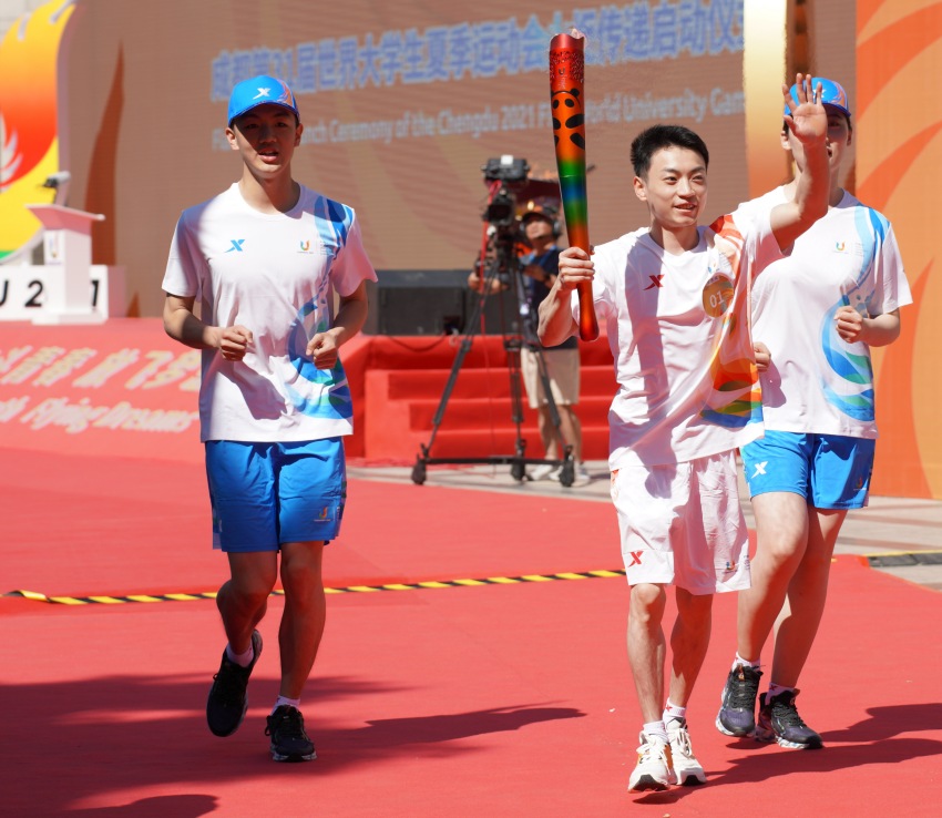 第一棒火炬手、成都體育學(xué)院學(xué)生、體操奧運(yùn)冠軍鄒敬園，高舉火炬昂首跑出會(huì)場(chǎng)。成都大運(yùn)會(huì)執(zhí)委會(huì)供圖