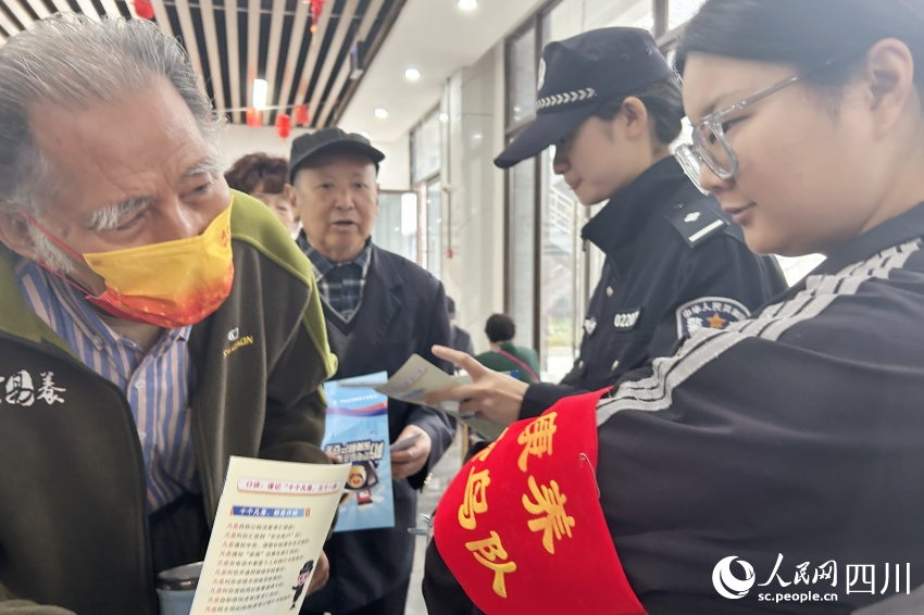 “康養(yǎng)候鳥隊”隊員為老人送上反詐宣傳資料。人民網(wǎng)記者 李平攝