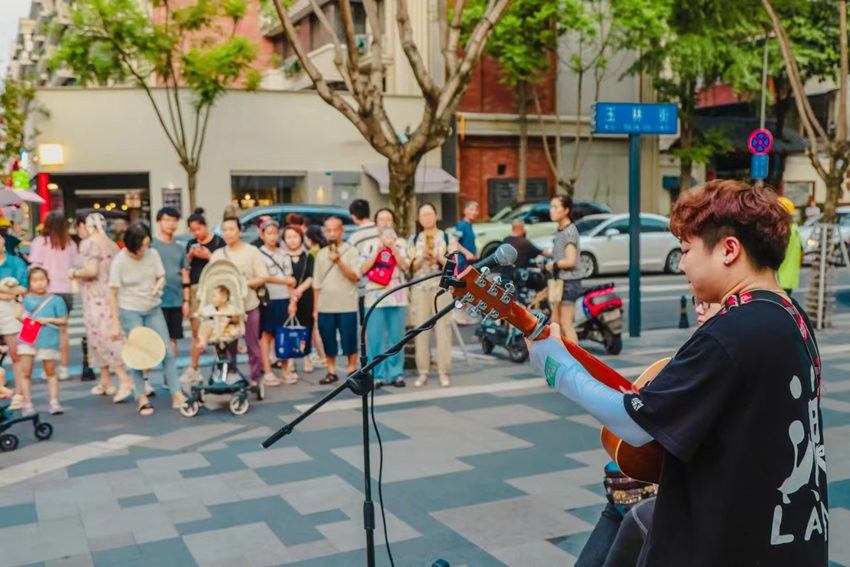 街頭藝人的表演深深吸引路人。玉林街道辦事處供圖