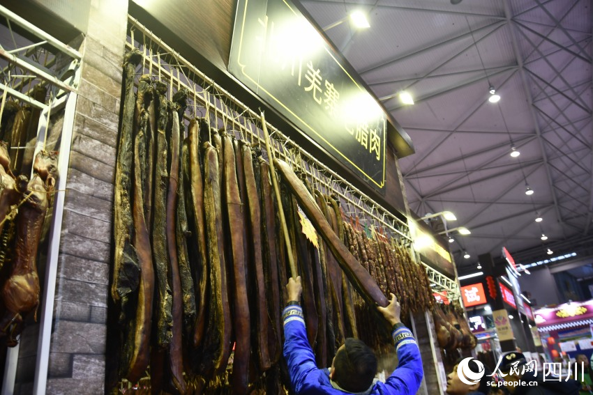 年貨節(jié)上，老板正在給顧客取臘肉。人民網(wǎng)記者 王洪江攝