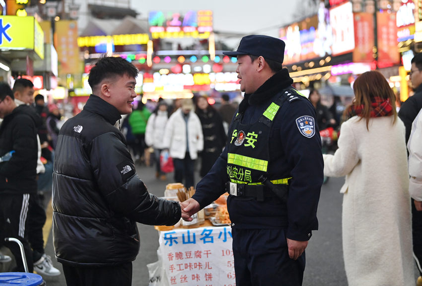 被幫助的游客和樂山市公安局市中區(qū)分局張公橋派出所副所長白科翔握手，表示感謝。樂山公安供圖
