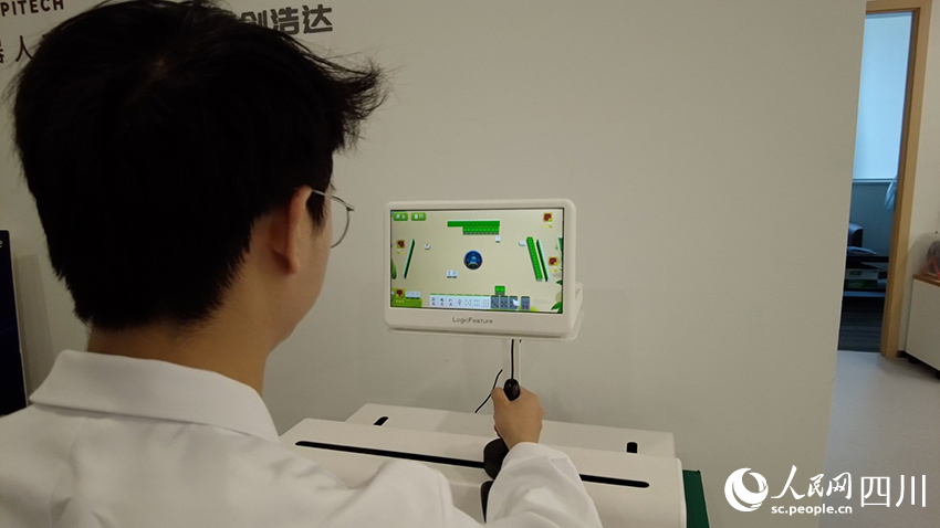 工作人員正在演示上肢康復(fù)機器人。人民網(wǎng)記者 郝帥攝