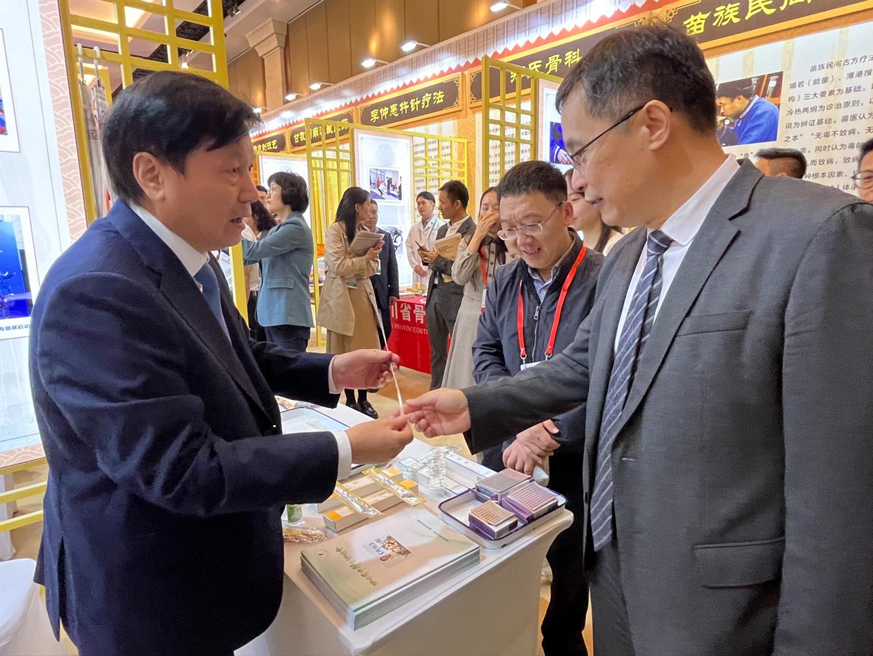 中醫(yī)藥展覽展示大會上，唐德厚（左）向國家中醫(yī)藥管理局副局長黃璐琦（右）介紹“唐氏芒針”。受訪者供圖