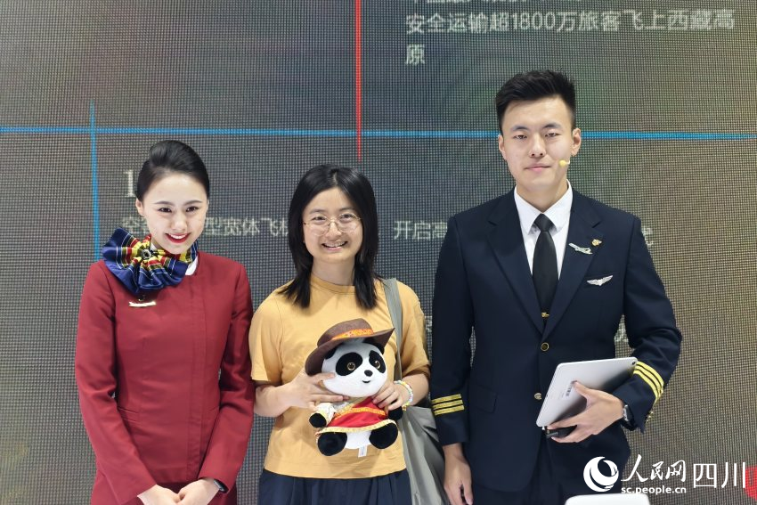 參與互動(dòng)的參展觀眾在領(lǐng)取禮物后同中國(guó)國(guó)際航空公司展館工作人員合影。人民網(wǎng) 趙祖樂(lè)攝