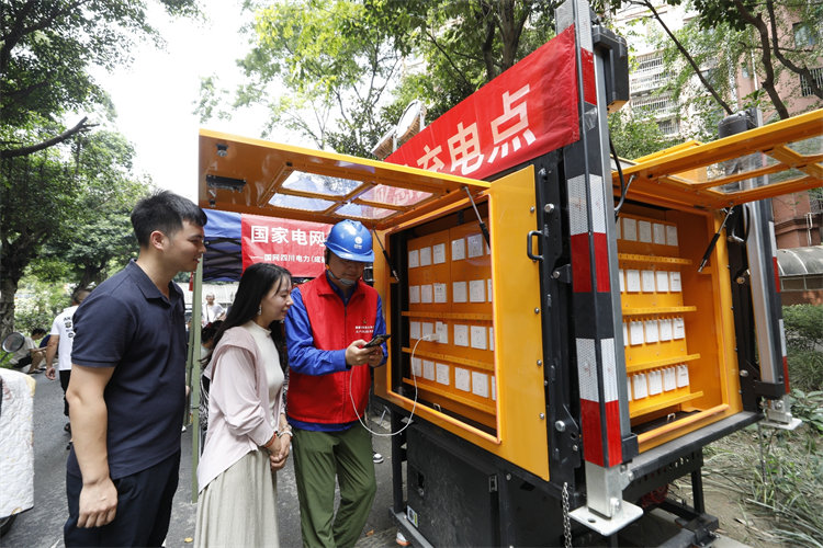 7月4日，在成華區(qū)銀鑼灣小區(qū)，國網(wǎng)成都供電公司成華供電中心設(shè)置應(yīng)急充電點(diǎn)，共產(chǎn)黨員服務(wù)隊(duì)隊(duì)員為居民提供現(xiàn)場(chǎng)充電服務(wù)。陳紅梅攝