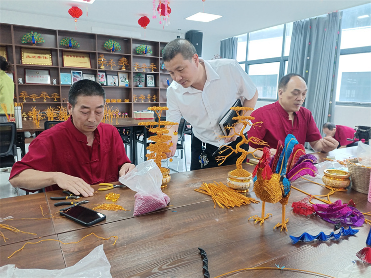 袁其濤（中）指導員工做工藝品。劉保剛供圖