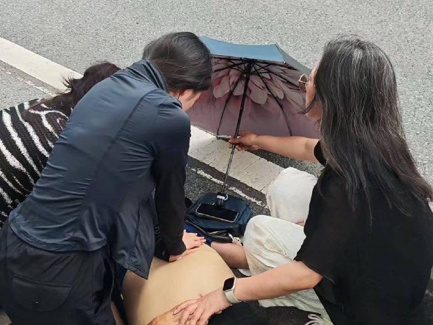 張璐瓊跪在路面上，對老人進行心肺復蘇。達州融媒供圖