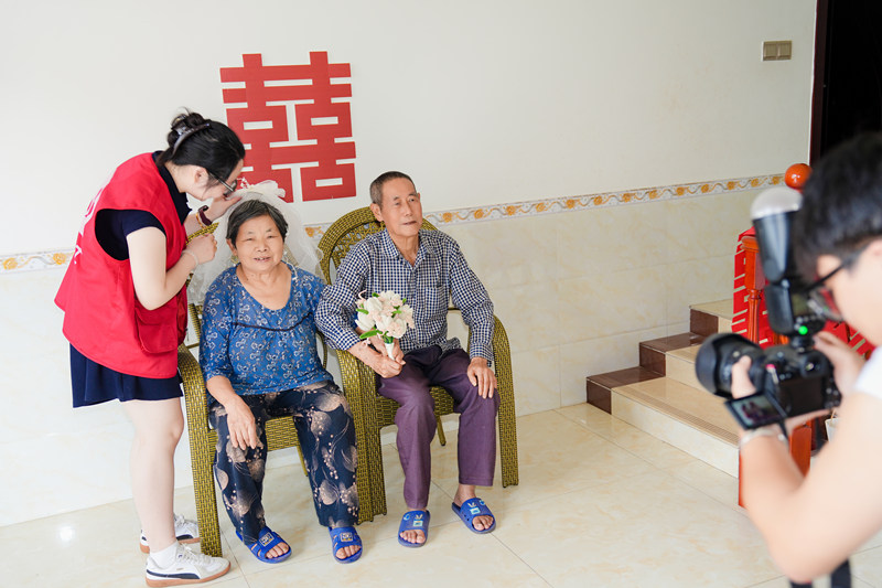 志愿者為金婚夫婦拍攝合照現(xiàn)場(chǎng)。余文攝